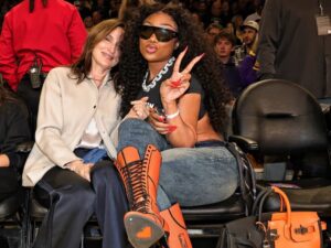 Megan Thee Stallion Courtside in Orange Lace-Up Heels and a Black-and-Feu Hermès Casaque HAC Bag at the Mavs vs. Lakers Game